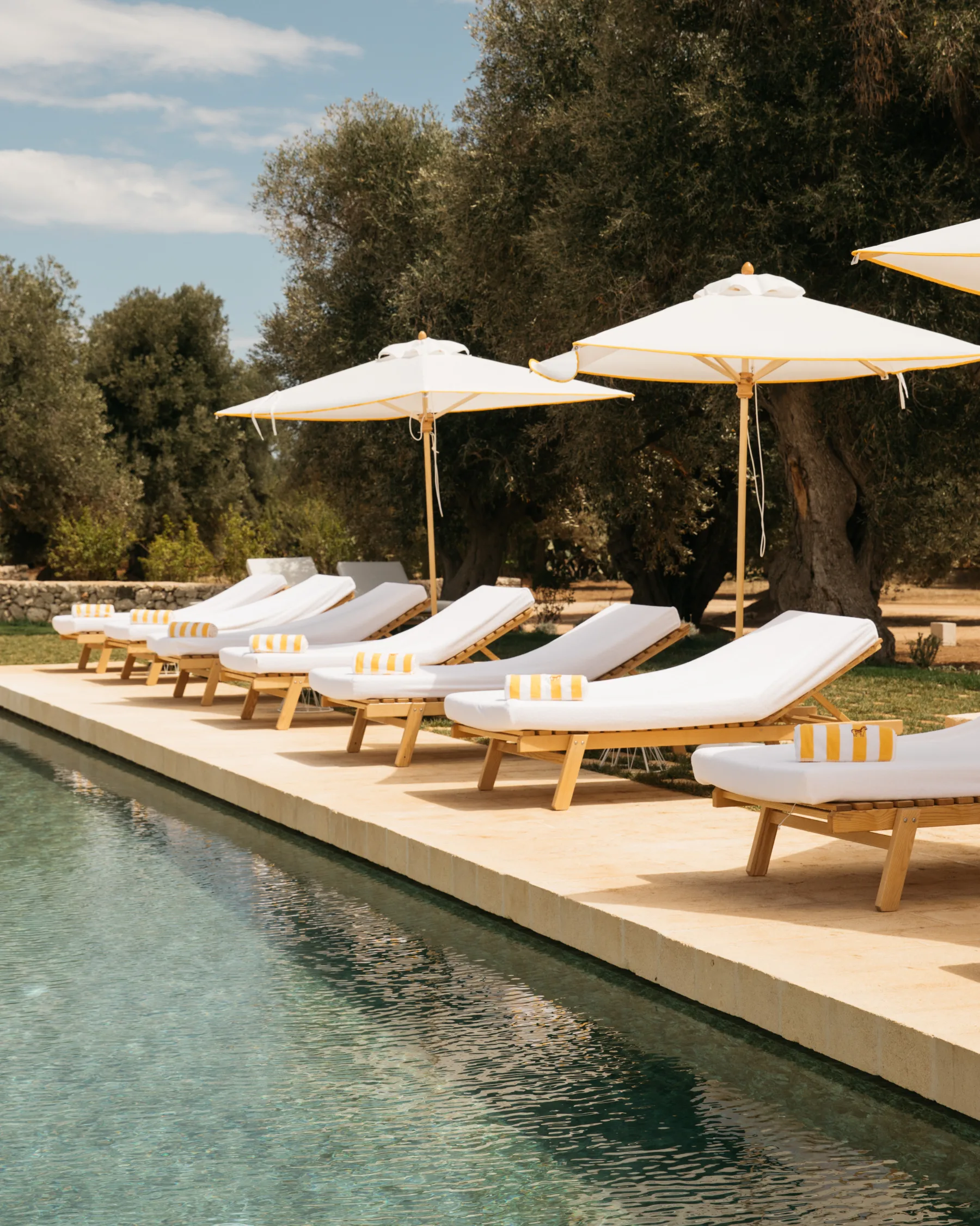 Poolside loungers and parasols set in line at Masseria Calderisi, Puglia