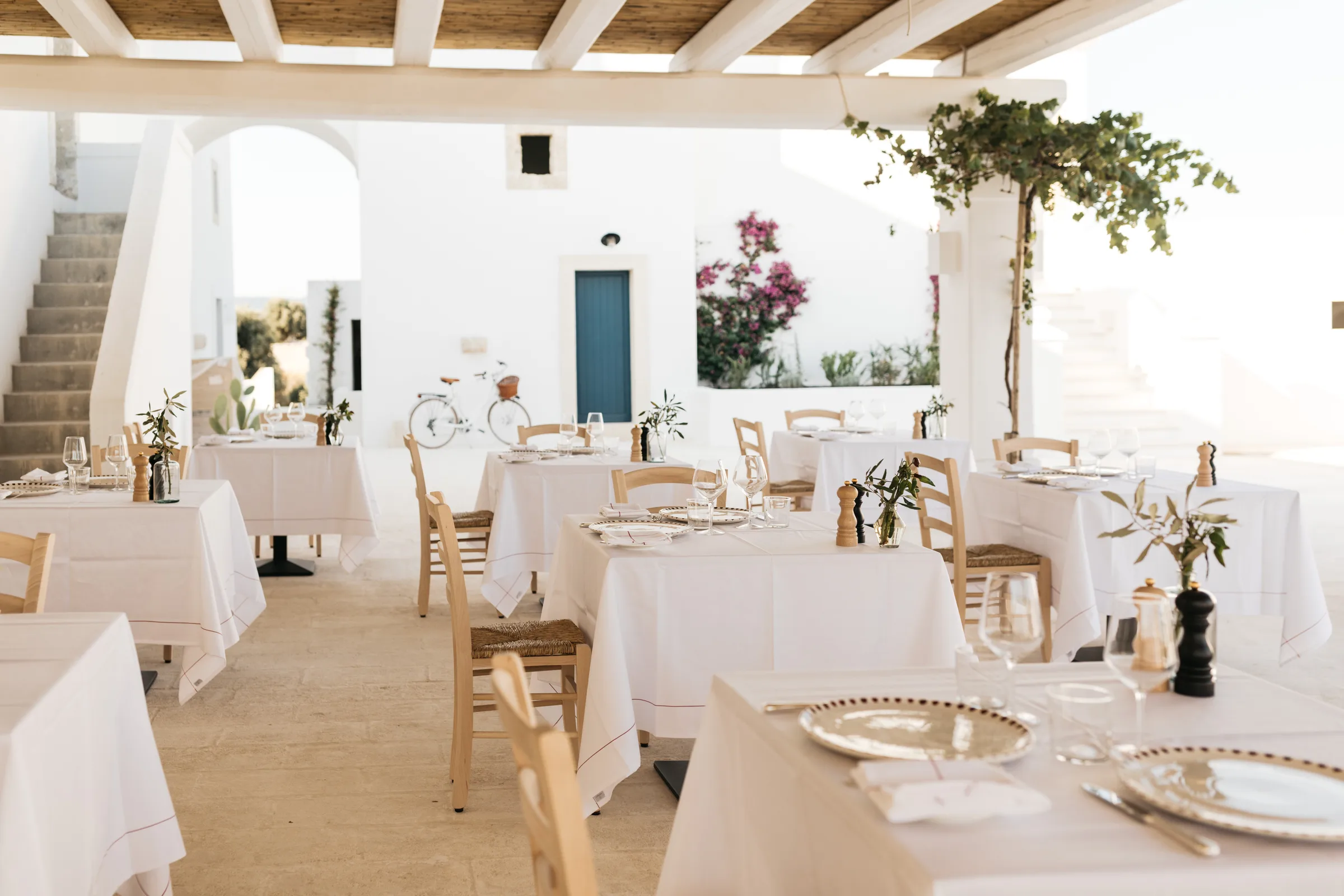 Laid tables under the pergola at Masseria Calderisi, whitewashed courtyard with bougainvillea beyond